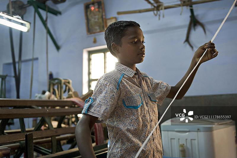 在印度南部泰米尔纳德邦卡鲁尔蚊帐工厂工作的童工图片素材