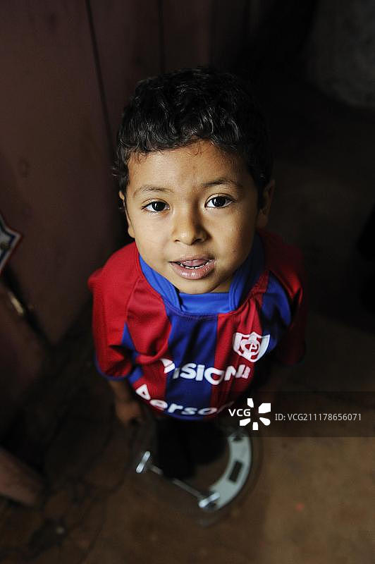 男孩站在体重秤上，援助组织在巴拉圭卡瓜苏省马蒂略社区检查儿童图片素材