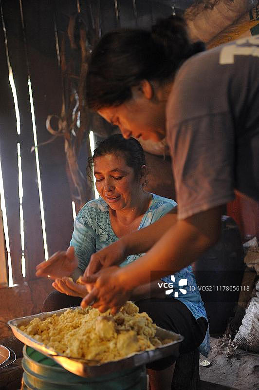 在简陋厨房用明火烹饪玉米饺子汤的妇女，巴拉圭卡瓜苏省马蒂略社区图片素材