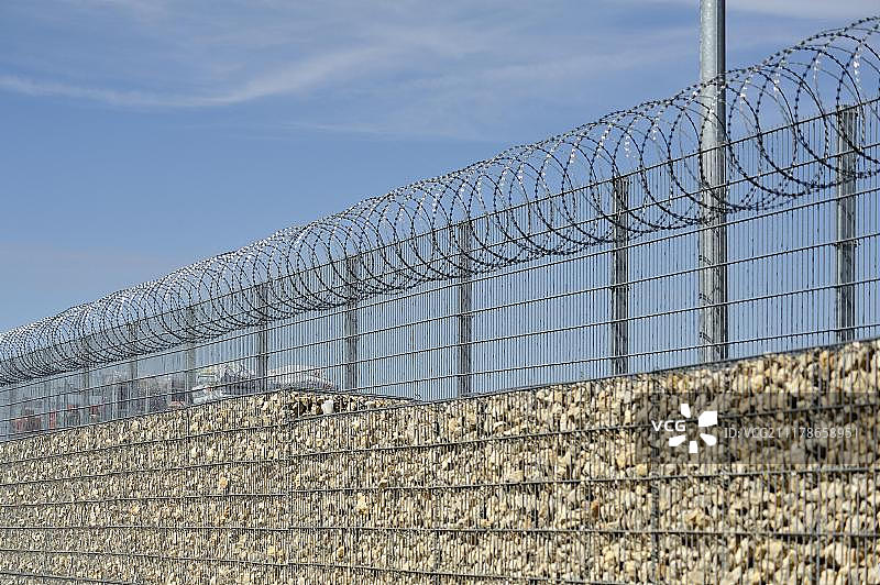 建筑中心储料场前的噪声屏障和带刺铁丝安全围栏，德国巴伐利亚州埃肯塔尔图片素材