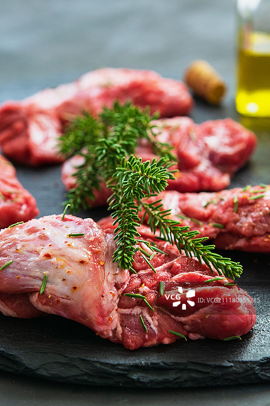 带有迷迭香和香料的深灰色表面上的生猪脸肉图片素材