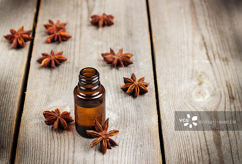 木桌上的八角茴香，周围放着一小瓶天竺葵油图片素材