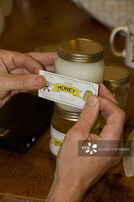 给琉璃苣蜂蜜罐贴标签图片素材