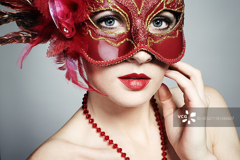 戴着红色神秘威尼斯面具的美丽年轻女人图片素材