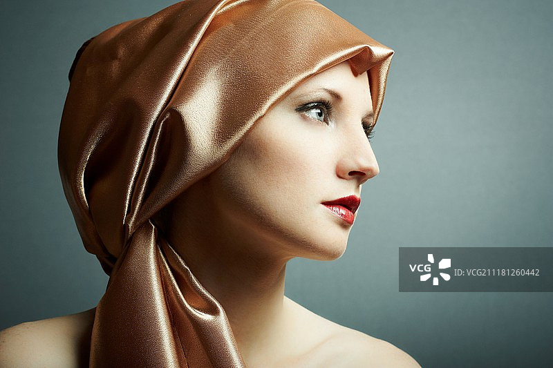 头上戴着金色围巾的年轻女孩的肖像图片素材