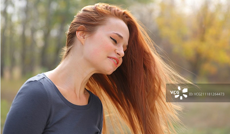 在公园里玩耍的年轻红发女子图片素材