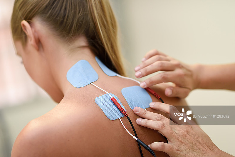 年轻女子接受物理治疗中的电刺激，在理疗中心进行肩部医疗检查。图片素材