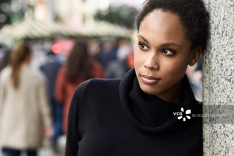 站在城市街道上的年轻黑人女性，穿着高领毛衣和裙子的混血女人图片素材