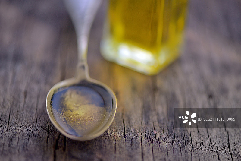 木桌上盛满橄榄油的勺子图片素材