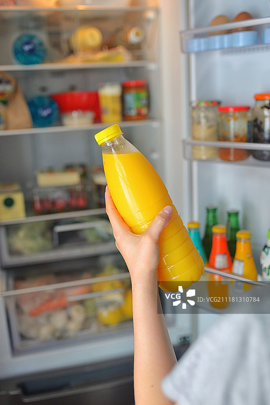 少女从冰箱里拿橙汁图片素材