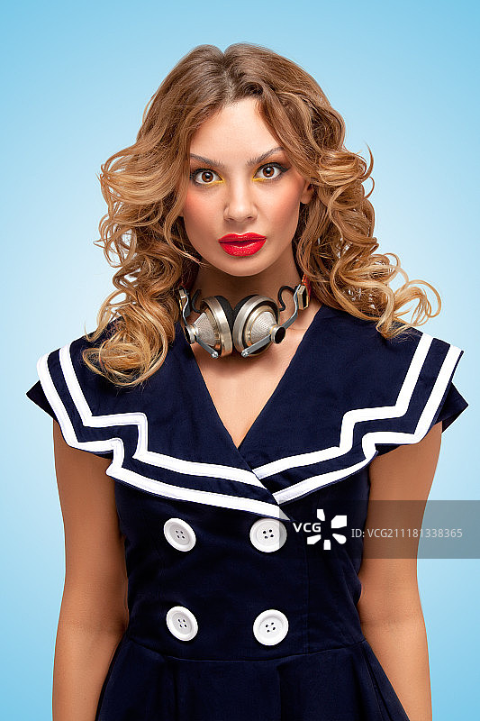 复古照片：时尚水手女郎戴复古金属耳机，蓝色背景图片素材