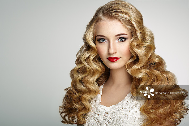 拥有金色波浪和闪亮长发的漂亮女孩。拥有卷发的金发女人。完美的妆容。时尚照片图片素材