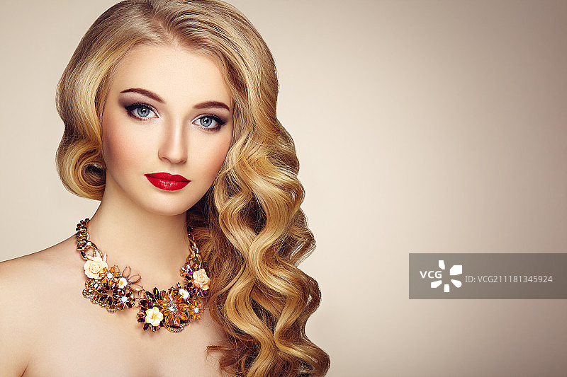 佩戴珠宝和优雅发型的年轻漂亮女性时尚肖像。长波浪金发女孩。完美妆容。美妆模特图片素材