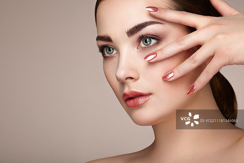 妆容精致的漂亮黑发女子：红唇美甲，完美眉形，粉底护肤。米色背景下的美丽女孩时尚照图片素材