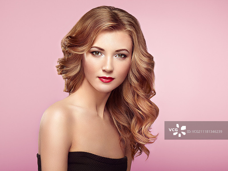 拥有蓬松亮丽波浪长发的金发女人。 妆容精致的美丽模特图片素材