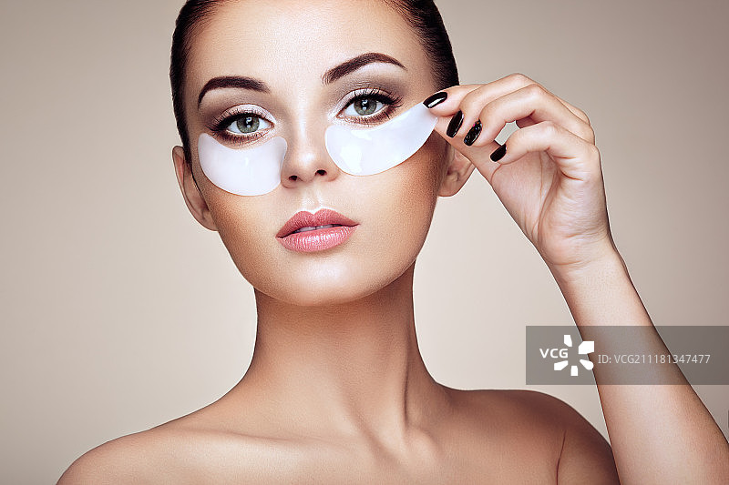 展现完美肌肤效果的眼膜美女肖像。年轻女子在米色背景下，拥有干净清新的皮肤和裸露的肩膀。棕发水疗女孩。图片素材
