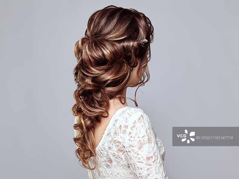 拥有长而有光泽的卷发的深棕色头发的女人。拥有卷发的漂亮模特女士。头发护理和美容产品。头发的护理和美容图片素材