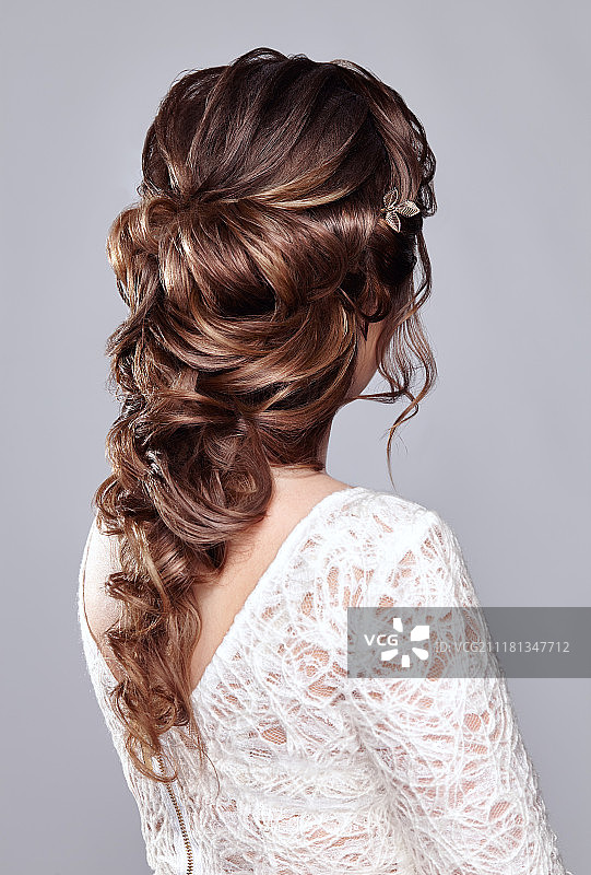 拥有长而有光泽的卷发的深棕色头发的女人。拥有卷发的漂亮模特女士。头发护理和美容产品。头发的护理和美容图片素材