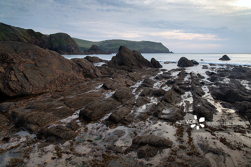 英格兰霍普湾岩石海岸线的日落海景图片素材