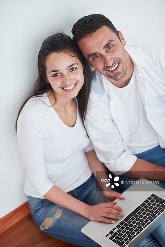 在现代家居室内使用笔记本电脑的快乐年轻夫妇图片素材