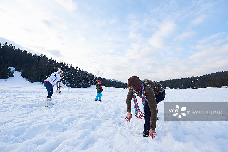 幸福的年轻家庭在阳光明媚的冬日户外玩雪图片素材