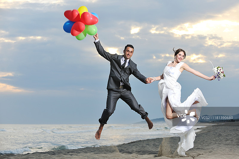 新婚夫妇在美丽的海滩日落时庆祝图片素材