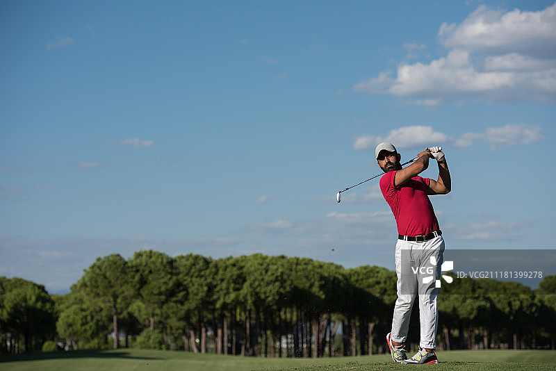 高尔夫球手在阳光明媚的日子里用发球杆击球图片素材