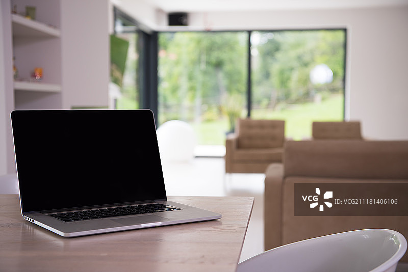 豪华客厅桌面上带有空白屏幕的笔记本图片素材