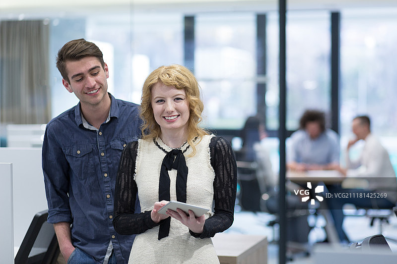 商务人士使用平板电脑为下次会议做准备，同事在创业办公室讨论想法图片素材