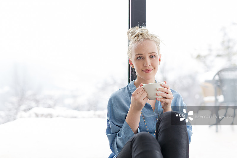 寒冷冬日，女人在地板上用笔记本电脑喝咖啡放松图片素材