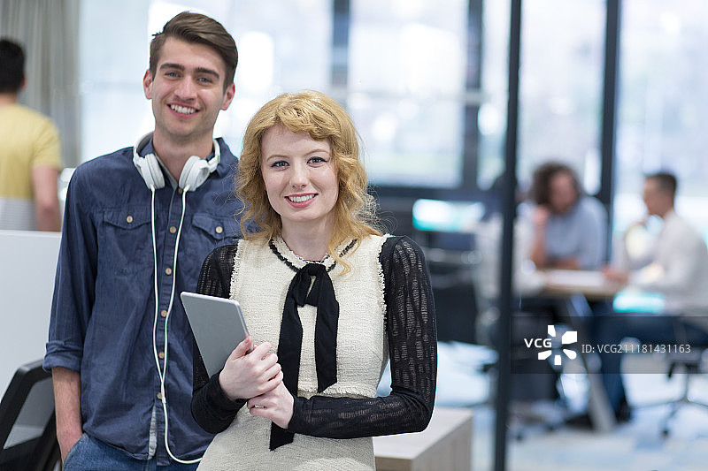 商务人士使用平板电脑为下次会议做准备，同事在创业办公室讨论想法图片素材