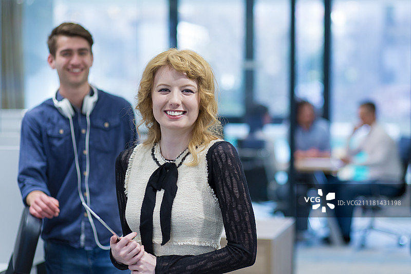 商务人士使用平板电脑为下次会议做准备，同事在创业办公室讨论想法图片素材