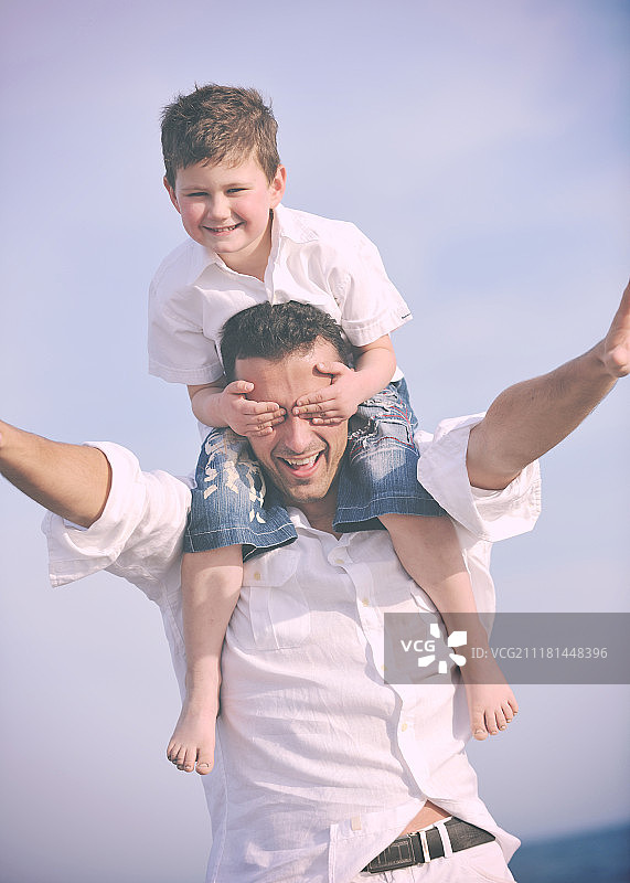 快乐的年轻父子在日落时分在海滩上玩耍，享受时光，代表着健康的家庭和支持图片素材