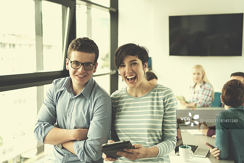 使用平板电脑的商人在背景中与同事讨论想法，为下次会议做准备图片素材