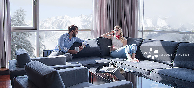 年轻夫妇在家中使用平板电脑在客厅沙发上阅读图片素材