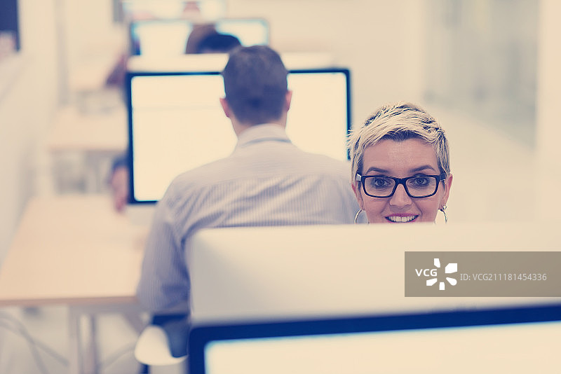 创业公司，在创意现代办公室放松娱乐的女人使用台式电脑工作图片素材