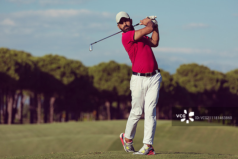 高尔夫球手在阳光明媚的球场上用发球杆击球图片素材