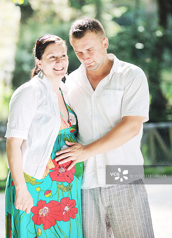 快乐的孕妇夫妇在阳光明媚的公园里享受乐趣和浪漫时光图片素材