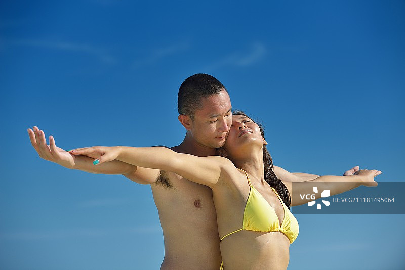 快乐的亚洲年轻夫妇在美丽的白色沙滩上享受浪漫时光图片素材