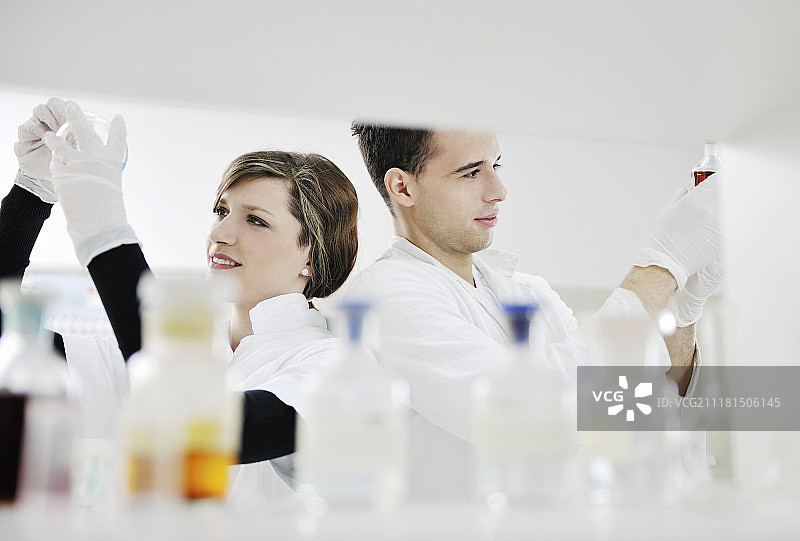 在明亮实验室里做实验的年轻学生情侣图片素材