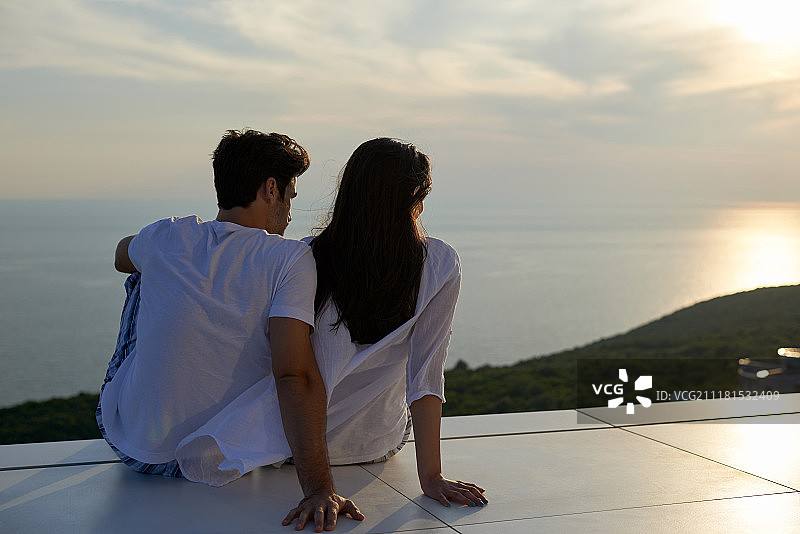 快乐的年轻情侣在现代住宅的户外阳台上玩耍放松，微笑图片素材