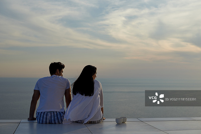 快乐的年轻情侣在现代住宅的户外阳台上玩耍放松，微笑图片素材