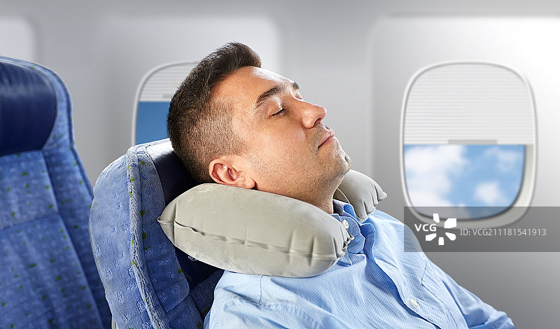 旅行舒适人物概念：男子在飞机上使用颈枕于舷窗背景前睡觉图片素材