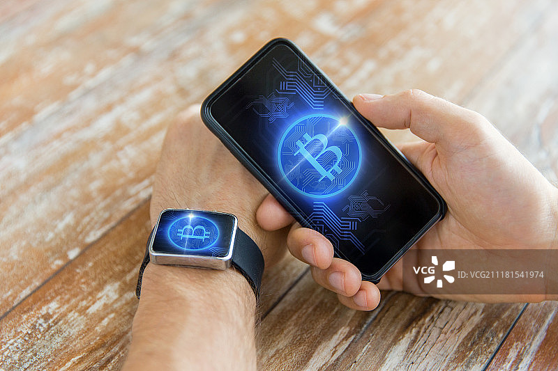 商务、科技和加密货币概念：手持智能手机和智能手表，屏幕上显示比特币图片素材