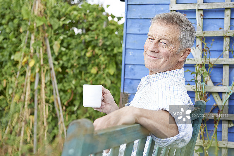 老年男人在花园里喝咖啡放松图片素材