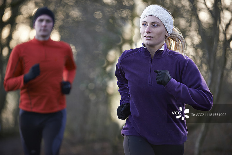 情侣在冬季的树林中跑步图片素材
