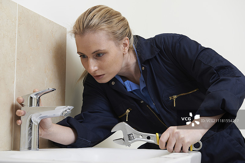 用扳手修理水槽的女水管工图片素材