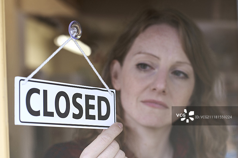 店主在商店门口翻转“已关闭”标志图片素材