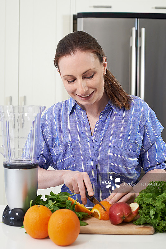 在厨房切水果准备放入榨汁机的女人图片素材