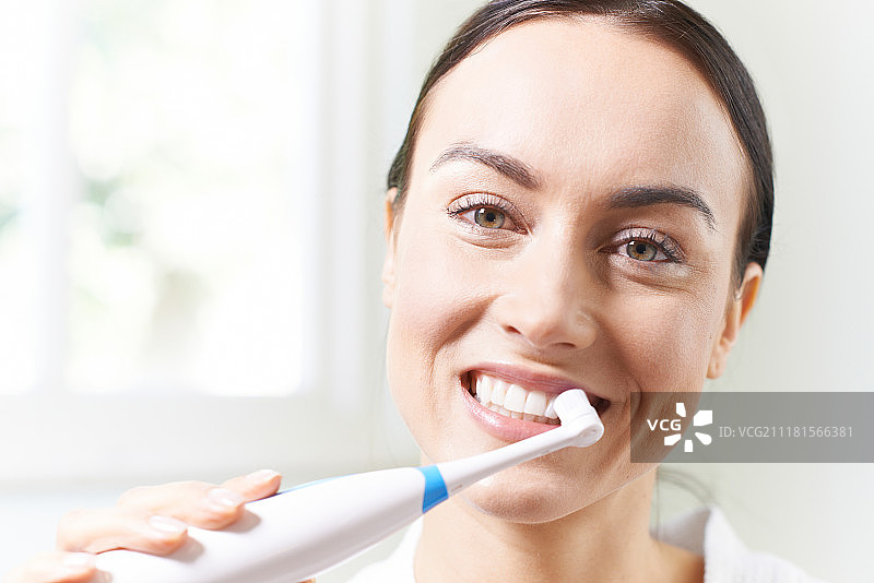 女人在浴室用电动牙刷刷牙图片素材